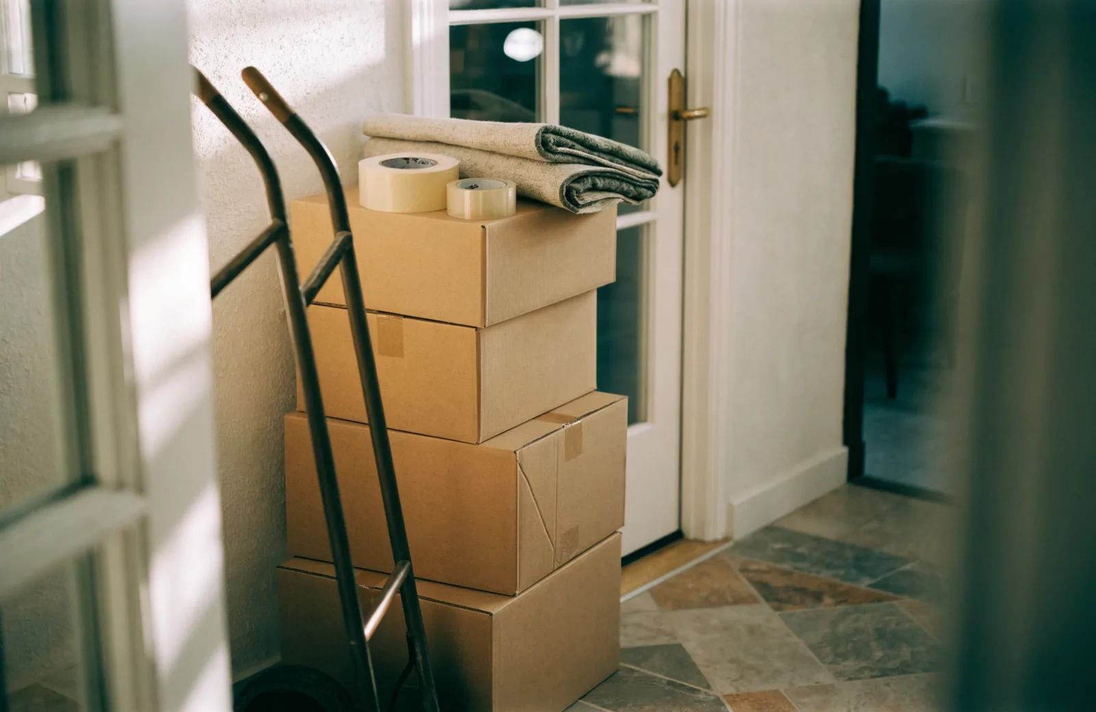 Packed moving boxes staged by the front door with a hand truck ready for loading